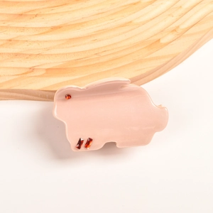 Détail d'une pince à cheveux cochon rose en acétate avec des strass rouges brillants