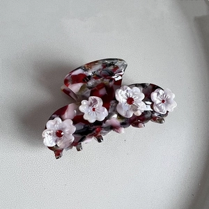 Detail einer floralen Haarklammer aus Acetat mit Marmor-Textur und weißen Blüten