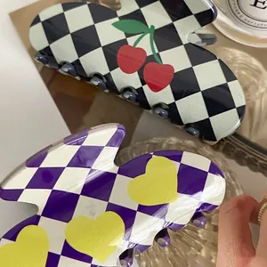 Detailed close-up of acetate hair claw clips with cherry and heart patterns