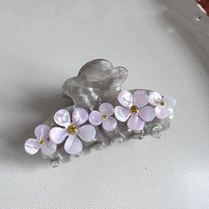 Detail von Haarklammer aus grauem Acetat mit lila Blumen und gelben Strasssteinen