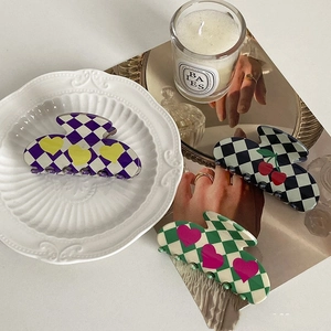 Detailed close-up of checkered acetate hair claws with cherry and heart patterns