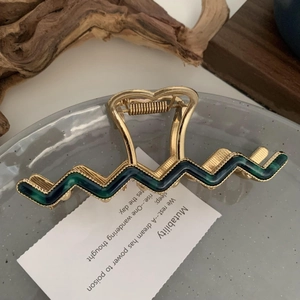 Detail of vintage wavy metal hair claw clip with emerald green enamel inlay and heart cutout