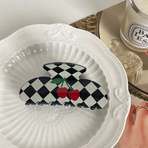 Detailed view of checkered claw clip with cherry motif on an elegant porcelain plate