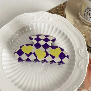 Detailed view of a purple and white checkered hair claw with yellow heart patterns