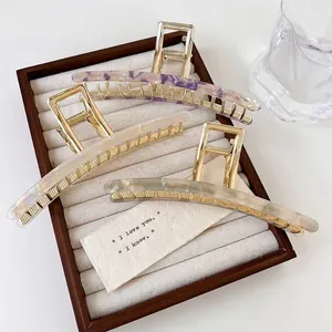 Three-piece acetate hair claw clips in purple and cream marble with golden metal teeth
