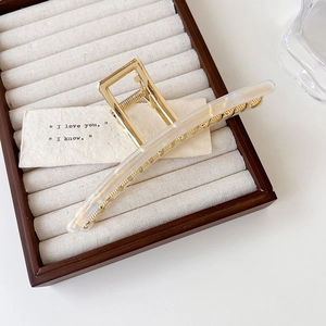 Macro view of a 13cm large gold metal claw clip with elegant ivory acetate accents