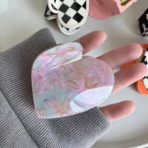 Pince à cheveux en acétate en forme de cœur avec motif marbré bleu tenue à la main