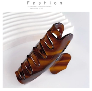 Detailed close-up of tortoise shell pattern acetate hair claw clip with golden spring
