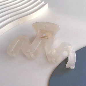 Detail view of cream wavy acetate claw clip with France Handmade engraving inside