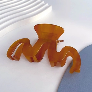 Detailed macro view showing France Handmade engraving on amber wave acetate hair claw clip