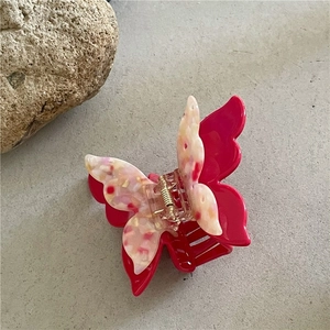 Detailansicht der Haarspange mit rosa Blumenmuster und rotem Schmetterling auf Steingrund