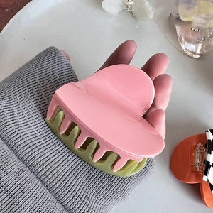 Vue détaillée d'une grande pince à cheveux en forme de cœur rose et vert contrasté