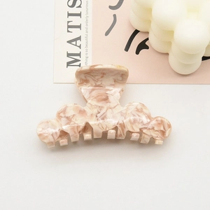 Gros plan détaillé d'une pince à cheveux en acétate marbré beige et rose de haute qualité