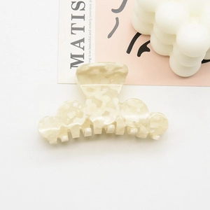 Détail d'une pince à cheveux en acétate blanc crème avec texture marbrée et dents solides
