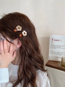 Détail de barrettes à fleurs en résine et boucle d'oreille perle sur cheveux