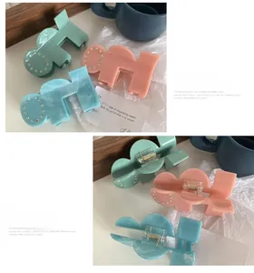 Detail of puzzle-shaped acetate hair claw clips with rhinestones in mint and pink colors