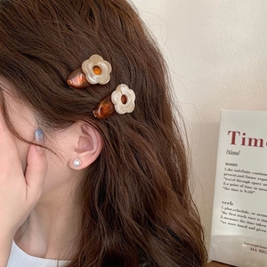 Lot de barrettes à fleurs minimalistes en résine ambre et crème portées sur le côté