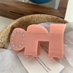 Close-up of pink acetate shark clip with round rhinestone pattern on a stone tray
