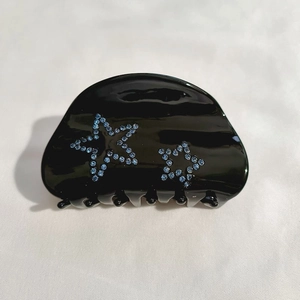 Détail d'une pince à cheveux noire en acétate avec motifs étoiles en strass bleus