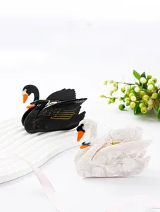 Detailed view of swan shaped acetate hair claws in black and white with feather texture