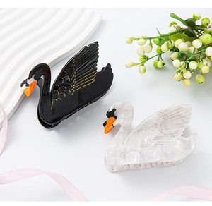 Detail of elegant swan hair claws featuring marble texture and gold wing accents