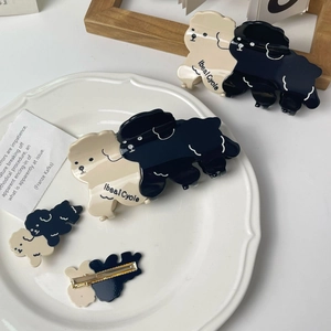 Lot de pinces à cheveux en acétate en forme de caniche crème posées sur une assiette