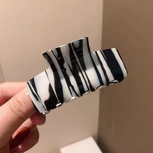Close-up of black and white ink texture acetate hair claw clip held in hand