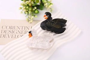 Detail of elegant swan-shaped acetate hair claws in black and marbled white with gold accents