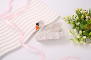 Close-up of elegant swan-shaped hair claw clip with marble texture and acetate finish