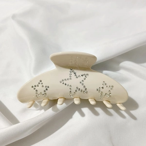 Detail of cream acetate hair claw clip featuring sparkling rhinestone star patterns