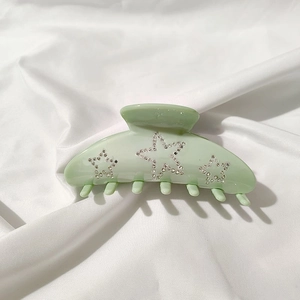 Close-up of large mint green acetate hair claw clip with sparkling rhinestone stars