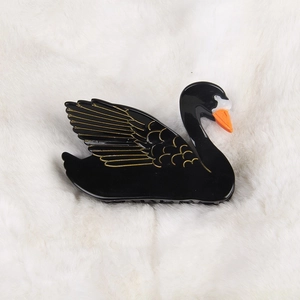 Elegant black swan acetate hair claw clip with gold accents on a soft plush background