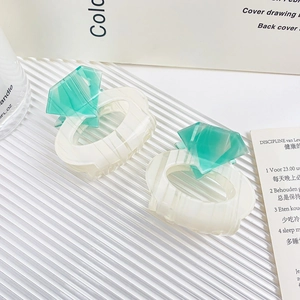 Elegant white and mint green diamond-shaped hair claws on a textured surface