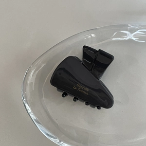 Detail of black acetate hair claw with gold Barrette La France text on glass plate
