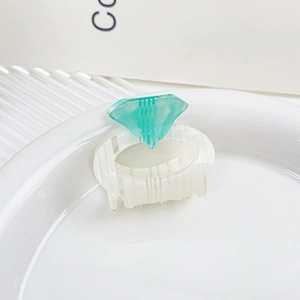 Detailed top view of a white striped hair claw clip with a turquoise diamond accent
