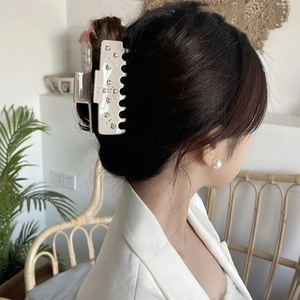 Elegant beige acetate claw clip with heart-shaped rhinestones worn on a woman's hair
