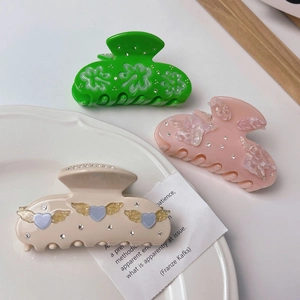 Three elegant acetate hair claws in green, pink, and ivory with heart and floral rhinestone accents