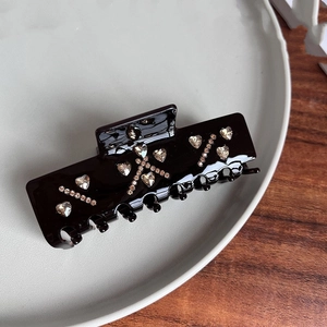 Detailed view of a black shark hair clip with heart-shaped rhinestones and crystal accents