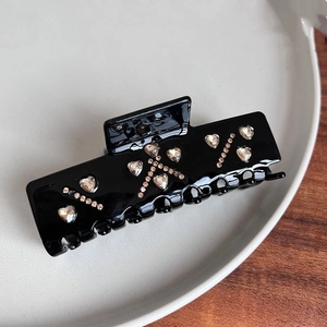 Detail of rectangular black acetate hair claw clip with inlaid sparkling heart rhinestones