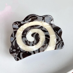 Detailed close-up of a large acetate hair claw with black and white spiral marble texture