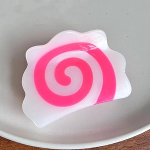 Macro view of unique Narutomaki spiral hair claw clip on a minimalist display tray