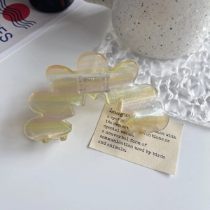 Detailaufnahme der gewellten irisierenden Blumen-Haarklammer auf einem Glastablett