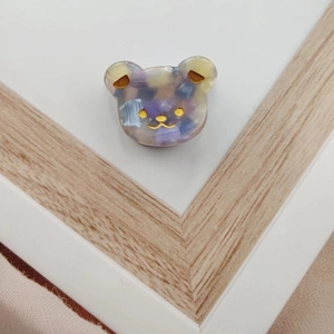 Detailed close-up of a colorful bear-shaped acetate hair claw with marble texture finish