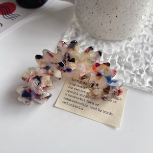 Detailaufnahme der Acetat-Haarklammer mit Marmormuster auf einem eleganten Tisch
