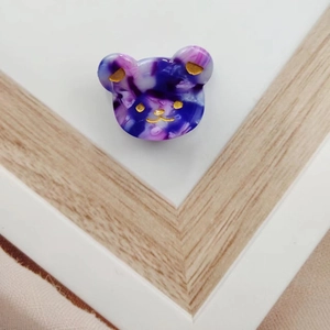 Close-up of marble pattern acetate bear hair clip with gold-tone accents and details