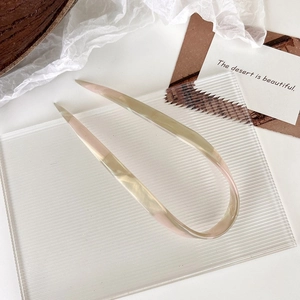 Detailed macro view of a minimalist U-shaped marble hair pin on a textured glass tray