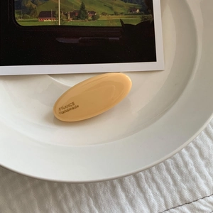 Detailaufnahme der cremegelben ovalen Haarspange mit France Handmade Gravur auf Keramik