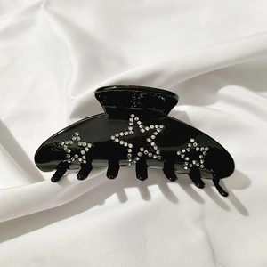 Glossy black hair claw clip featuring sparkling rhinestone star patterns on silk fabric