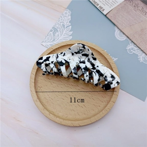 Detailed view of an 11cm cow pattern hair claw clip with a glossy acetate marble finish