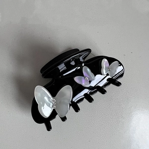 Detail of black acetate hair claw clip with iridescent rhinestone butterfly accents